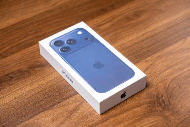 Poznan, Polonya - 16 Ekim 2025: iPhone 17 Pro perakende paketi ahşap üzerinde mavi cep telefonu, gelişmiş iletişim özellikleri ve tüketici elektroniği vurgulanıyor