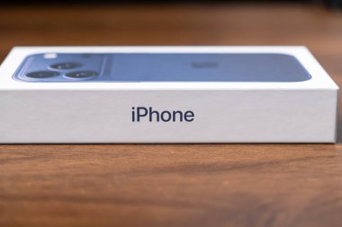 Poznan, Polonya - 16 Ekim 2025: iPhone 17 Ahşap yüzey üzerinde mavi akıllı telefon paketi, modern mobil teknoloji, yenilikçi tasarım ve küresel pazar