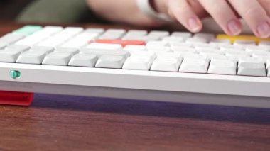 Etkin bir beyaz ve sarı klavye üzerinde aktif olarak tuşlara basan parmaklar, verimli veri girişini, uzaktan çalışmayı veya ahşap bir masa üzerindeki çevrimiçi etkinliği sembolize eder