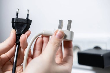 Eller, çeşitli güç standartları ve küresel seyahat ve ücret çözümleri için adaptör gereksinimleri gösteren farklı siyah Avrupa ve beyaz İngiliz elektrik prizlerini karşılaştırır