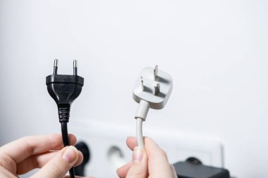 Cihaz şarj ve seyahat adaptörleri için küresel elektrik standartlarını vurgulayan Avrupa tip C ve İngiliz tip G 'yi karşılaştıran eller