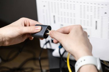 Karanlık bir ağ adaptörüne RJ45 Ethernet kablosu yerleştiren ellerin yakın plan görüntüsü, İnternet bağlantısı kurulumu, bilişim desteği ve güvenilir ağ yapılandırma süreçlerini vurguluyor
