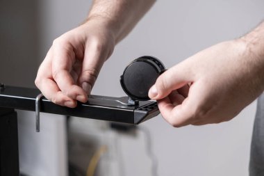 Verimli DIY mobilya kurulumu için altıgen anahtarı kullanarak sağlam bir metal çerçeveye dayanıklı siyah bir Caster tekerleği takan birinin ellerine yakın çekim.