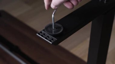Bir insanın elinin titizlikle düz siyah bir masa bacağındaki vidayı sıkarken ki bu da mobilya yapımı ve kişisel ev geliştirme sürecini gösteriyor.