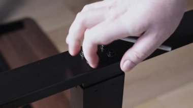 Bir el özenle siyah bir sürgüyü modern bir metal çerçeveye takmak için gümüş büyü anahtarını çeviriyor. Bu da dikkatli bir mobilya montajı ve ev kurulumunu gösteriyor.