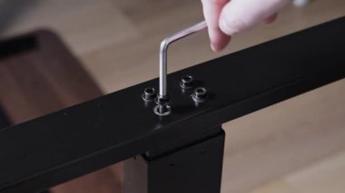 İnsan elinin titizlikle siyah bir sürgüyü Allen anahtarıyla koyu metal bir korkuluğa çevirmesi kişisel montaj ve binanın detaylarını gösteriyor. Büyüt