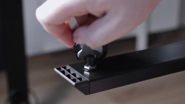 Bir insan elinin titizlikle siyah bir Caster tekerleğini İngiliz anahtarıyla mobilyaların üzerine yerleştirmesi ve emniyete alması, kurulum, bakım ve pratik ev gelişimini temsil ediyor.