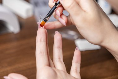 Bir kadının ellerinin, tırnak uzatmak için açık plastik bir çift biçime çoklu jel sürerken yakın plan çekimi, yaratıcı kişisel bakım ve DIY güzellik projesini vurguluyor