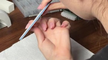 Bir insan manikür yaptırıyor, tırnaklarını nazikçe fırçalıyor ve manikür sürecini evde tek başına gösteriyor.