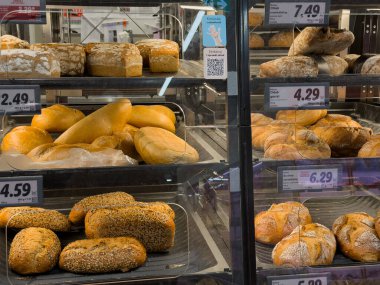 Poznan, Polonya - 29 Ekim 2025: Modern bir süpermarkette sergilenen çeşitli fırınlanmış ekmek somunları, baget ekmeği ve zanaatkar rulolarının yakın çekimi