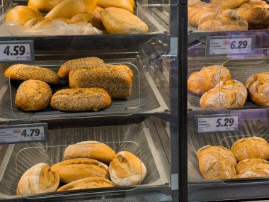 Poznan, Polonya - 29 Ekim 2025: Altın kabuklu ekmek ve rulo, taze pişmiş, temiz süpermarket raflarında sergileniyor, sağlıklı gıda seçenekleri sunuyor