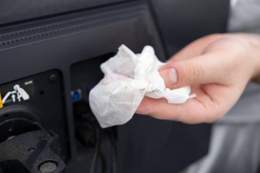 Kirli ıslak bir mendille yakın plan çekilmiş. Karanlık elektronik bir cihazın arka kapaklarından toz kaldırılmış. Temizlik ve bakım için kullanılan bir cihaz.