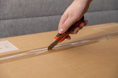 Bir kişinin elini dikkatlice bir maket bıçağıyla keserek yeni bir satın alma ya da başarılı bir teslimat beklentisinin altını çizmek.