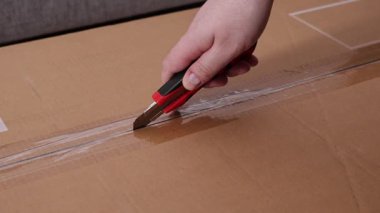 Bir paketin üzerindeki kırtasiye bıçağıyla şeffaf bandı dilimleme eylemi posta geldiğini, siparişin yerine getirildiğini, tüketiciliğin başladığını ve montajın başladığını gösterir. Büyüt