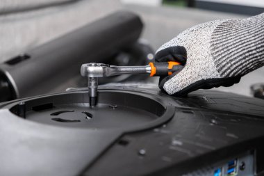 Eldivenli bir elin bilgisayar monitöründe kilit anahtarı kullanarak yakın plan çekimi. Detaylı elektronik tamirat, hassas montaj ve profesyonel bakım işlerini sembolize ediyor.