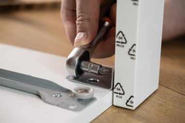 Vidaları takmak için cırcır tornavidayı kullanarak iç tasarım için yeni ev mobilyaları yaparak bir kişinin elini özenle yaklaş.