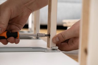 İnsan ellerinin yakın plan çekimleri, beyaz kendi kendine montaj kabinesinin panellerini güvence altına almak, ev kurulumunu, kendin yap inşaatını ve modern iç mekanlarda el işçiliğini vurgulamak.