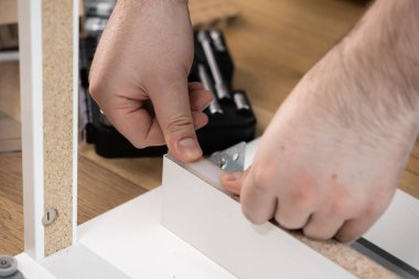 Yeni beyaz mobilyaları birleştiren, ev mobilyaları ve iç tasarım geliştirme sürecini temsil eden bir kişinin ellerinin yakın plan görüntüsü