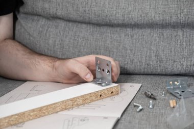 Erkek eller, montaj talimatları, vidalar ve paneller ile parçacık tahtasına metal parantez tamir ev mobilyaları DIY temsil
