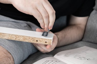 Modern DIY ev geliştirme ve pratik yaşam becerilerini sembolize eden beyaz parçacık tahtası mobilyalarının yapımını özenle izleyen bireyler