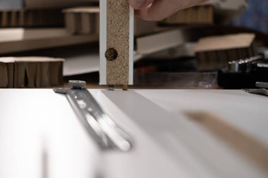 Beyaz parçacık paneline ahşap bir panel yerleştirme ve bir ev yenileme projesi için düz paket mobilya monte etme görüntüsü