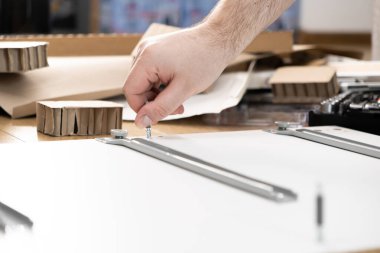 Yeni mobilyaların vidalarını sıkan bir elin yakın plan görüntüsü, düz paket parçaları montajı ve pratik ev yenileme çalışmalarının ayrıntılı çalışmalarını vurguluyor