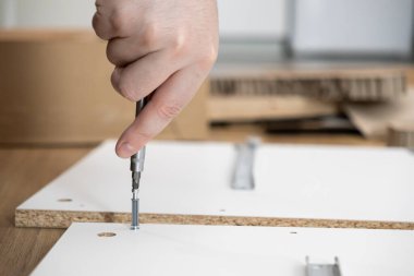 İnsan elinin titizlikle beyaz parçacık tahtası mobilya panellerini birbirine vidalaması, kendiliğinden montaj, işçilik ve yerli mobilya projelerini sergilemesi.