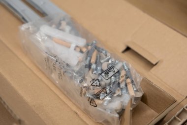 Düz paket mobilya montaj projeleri için çeşitli metal vidalar, ahşap kaplamalar ve plastik konnektörlerle dolu şeffaf bir plastik torba yakın plan