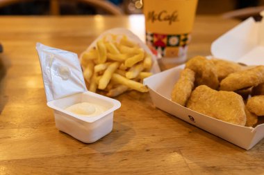 Poznan, Polonya - 19 Kasım 2025: Bir McDonald 's McCafe içeceği, çıtır çıtır tavuk nuggetları, taze patates kızartması ve bir açık sos kabı hızlı yemek için sunuluyor
