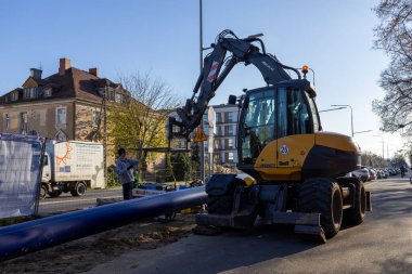 Poznan, Polonya - 21 Kasım 2025: Ağır makineler, bir işçi ve kamu işleri projesi için yeni bir boru hattı olan modern bir şantiyenin ayrıntılı görünümü
