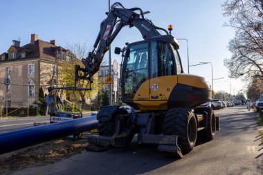 Poznan, Polonya - 21 Kasım 2025: MECALAC kazıcı, önemli şehir hizmetleri kurulumu için mavi boru hattını dikkatlice yerleştirerek, kentsel kamu çalışmalarına aktif olarak dahil oldu