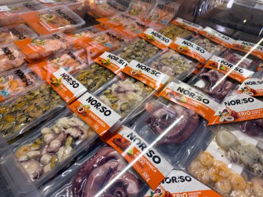 Poznan, Polonya - 28 Kasım 2025: Modern bir süpermarkette müşteri alımı için sunulan ahtapot, karides ve midye gibi çeşitli paketlenmiş deniz ürünlerinin yakın görüntüsü