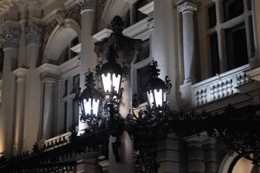 Krakow, Polonya - 30 Kasım 2025: Süslü lamba, klasik mimari ve zarif şehir cazibesini vurgulayarak, büyük eski bina cephesine parlak ışık tutuyor