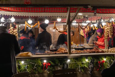 Krakow, Polonya - 30 Kasım 2025: Bustling market sosis de dahil olmak üzere lezzetli sıcak ızgara yemekleri çeşitli müşterilere sunuyor.