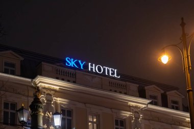 Krakow, Polonya - 30 Kasım 2025: SKY HOTEL tabelası, parlayan mavi-beyaz, bina üzerinde duruyor, şehir gece gezginleri için yol gösterici