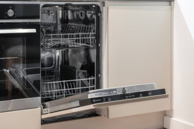 Krakow, Polonya - 30 Kasım 2025: Kapısı aralık olan çağdaş entegre bulaşık makinesi, temiz rafları ve sezgisel kontrol panelini ortaya çıkarıyor, mutfak verimliliğini artırıyor