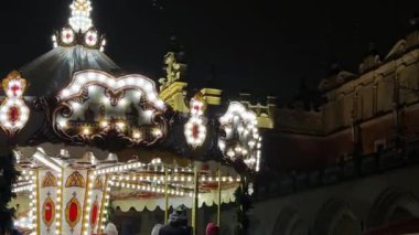 Krakow, Polonya - 30 Kasım 2025: Aydınlatılmış neşeli atlıkarınca ayrıntıları, karmaşık altın desenler ve parıldayan ampuller, kış tatili kutlamaları için mükemmel