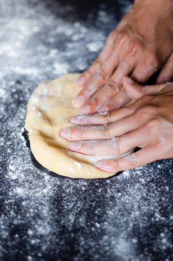 Siyah arka planda hamur yoğurmak. Undan hamur yapmak, yemek pişirme ve beslenme hakkında bir blog için fotoğrafla çelişmek. Kadın elleri.