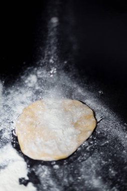 Siyah arka planda hamur yoğurmak. Un ile hamur yapmak, yemek pişirme ve beslenme hakkında bir blog için zıt fotoğraf.