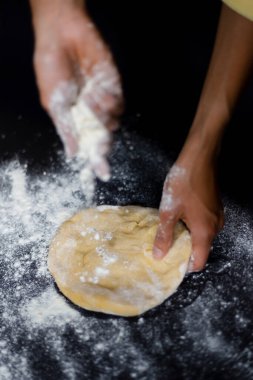 Siyah arka planda hamur yoğurmak. Undan hamur yapmak, yemek pişirme ve beslenme hakkında bir blog için fotoğrafla çelişmek. Kadın elleri.