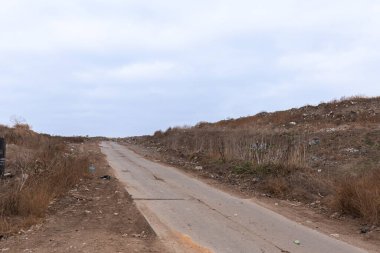 Fıçı yolu. Çöp yığını, çöp tepeleri arasında tek bir yol var. Atık tasnif ve geri dönüşüm istasyonlarında yangın güvenliği için çöplere kum serpilmiştir..