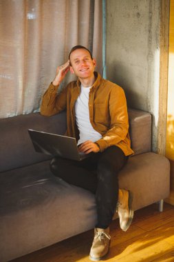 Genç yetişkin adam gündüzleri dinlenme odasında çalışıyor.