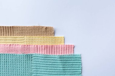 Beyaz arka planda düzgün bir yığın halinde düzenlenmiş renkli mikrofiber havlular. Temizlik, mutfak kullanımı ve ev organizasyonu için çeşitli renklerde parlak ev ürünleri.