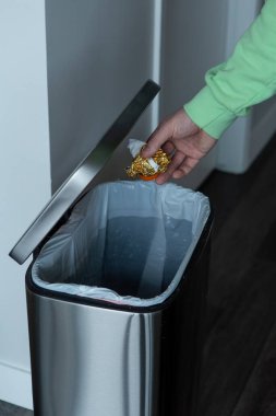 Büyük metal bir çöp kutusuna plastik şişe atmak. Evde çöp ayıklama.