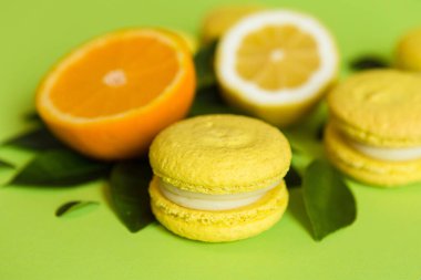 Limon aromalı badem kurabiyeleri turunçgiller ve yapraklarla yeşil bir zemin üzerinde yatar.