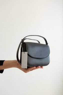Bir mankenin elinde siyah, küçük bir kadın çantası. Modern moda bir el çantasının fotoğrafı. Günlük hayatta şık aksesuarlar. Ayrıntılı kadın toplantıları.