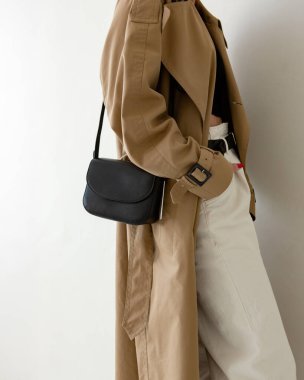 Bir modelin üzerinde siyah küçük bir kadın çantası. Modern moda bir el çantasının fotoğrafı. Günlük hayatta şık aksesuarlar. Ayrıntılı kadın toplantıları.