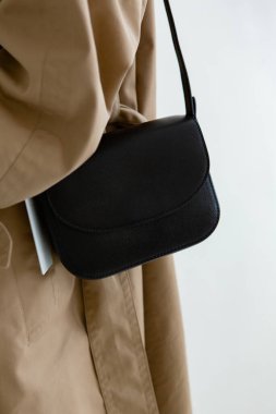 Bir modelin üzerinde siyah küçük bir kadın çantası. Modern moda bir el çantasının fotoğrafı. Günlük hayatta şık aksesuarlar. Ayrıntılı kadın toplantıları.