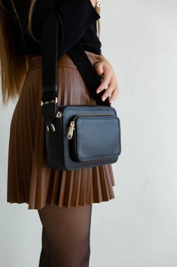 Bir modelin üzerinde siyah küçük bir kadın çantası. Modern moda bir el çantasının fotoğrafı. Günlük hayatta şık aksesuarlar. Ayrıntılı kadın toplantıları.