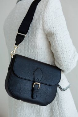 Bir mankenin elinde siyah, küçük bir kadın çantası. Modern moda bir el çantasının fotoğrafı. Günlük yaşamda şık aksesuarlar.